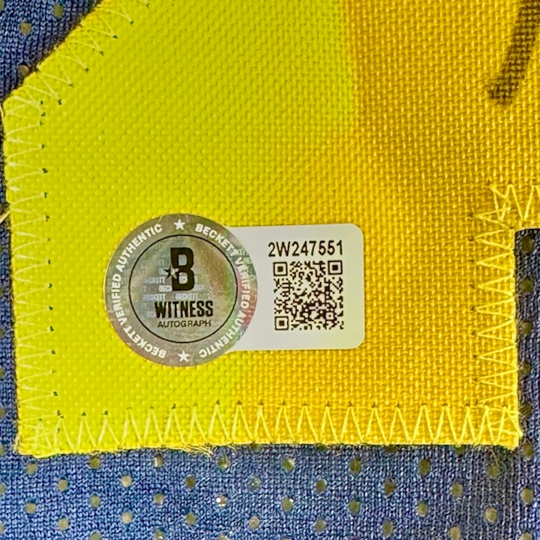Close up of Beckett Witness Authentication holo sticker at top left of 2 in yellow 23 stitched on reverse of jersey.