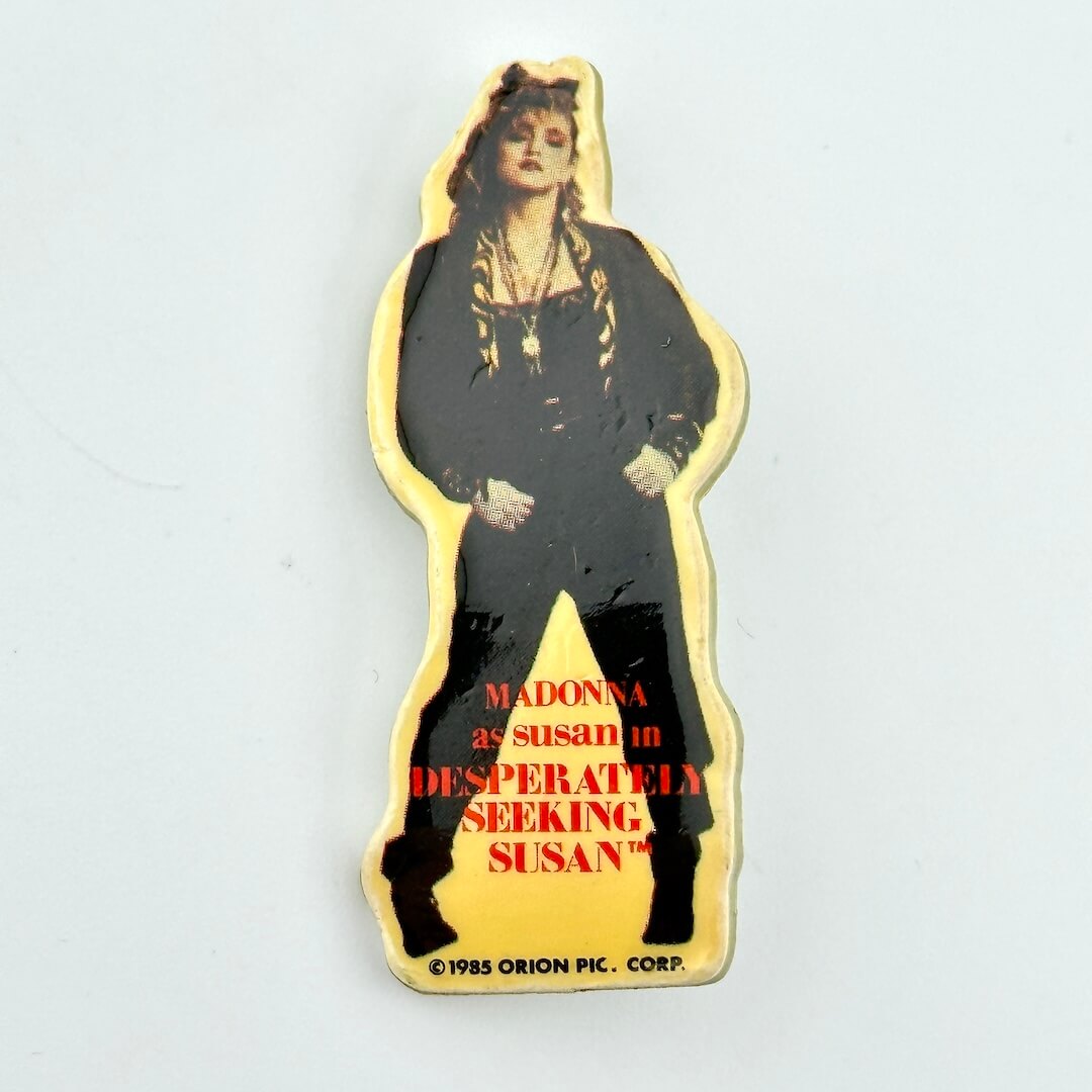 Promotional cutout pin of a actress from 'Desperately Seeking Susan' with text on a light gray background