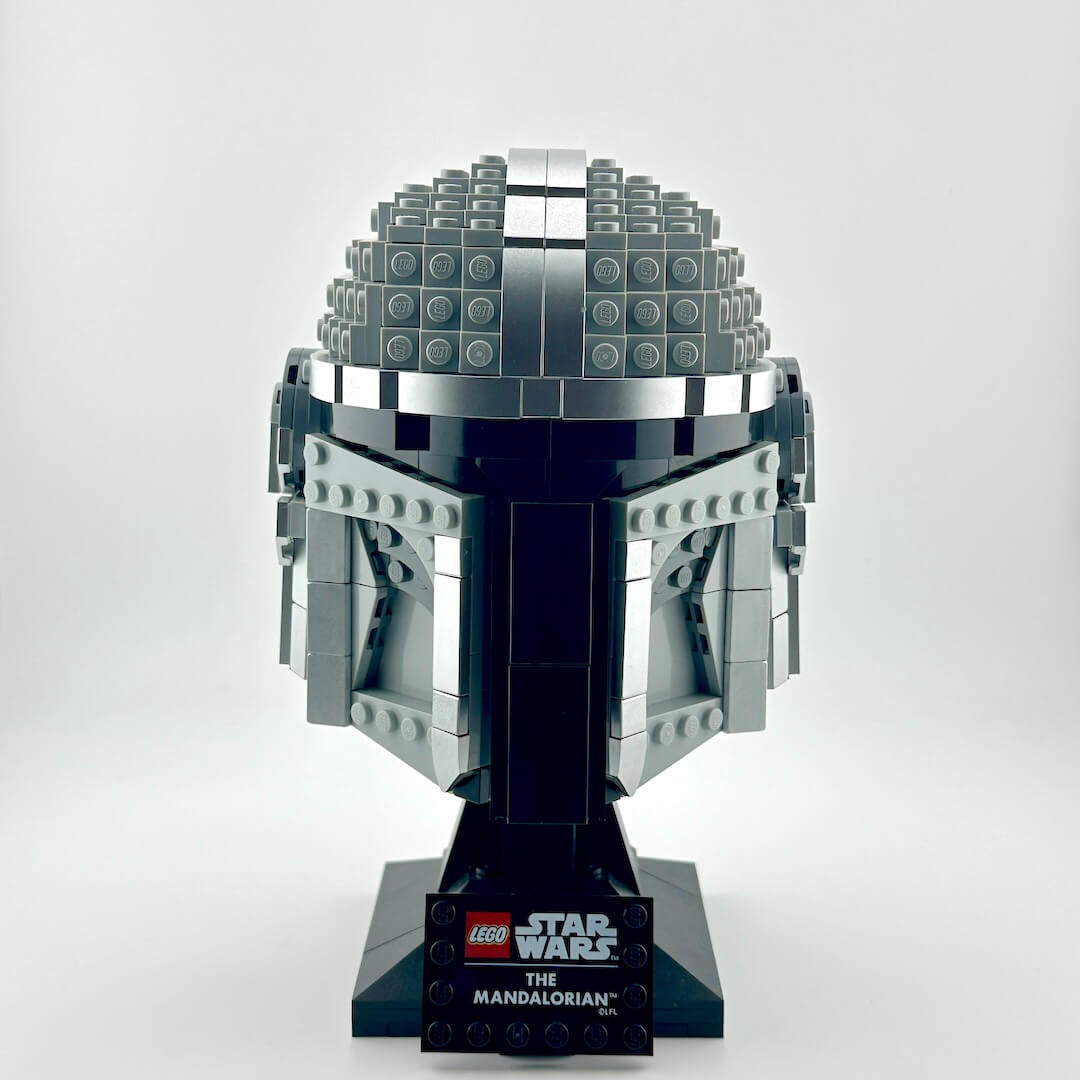Lego Mandalorian helmet on stand against white background.