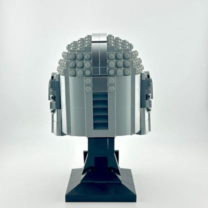 Lego Mandalorian helmet on stand against white background.