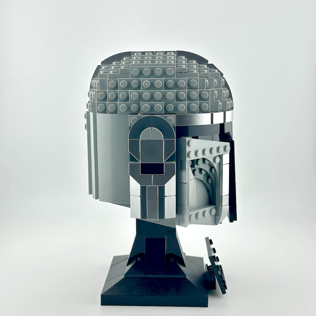 Lego Mandalorian helmet on stand against white background.