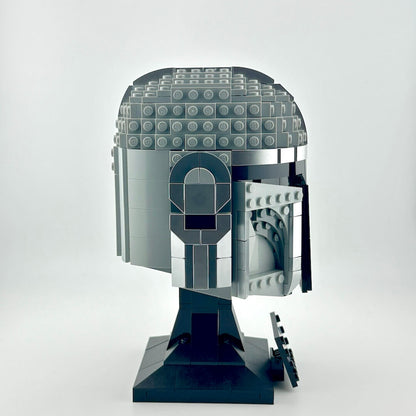 Lego Mandalorian helmet on stand against white background.
