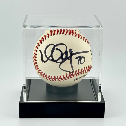 Autographed baseball in plastic cube with black base and black marker signature.