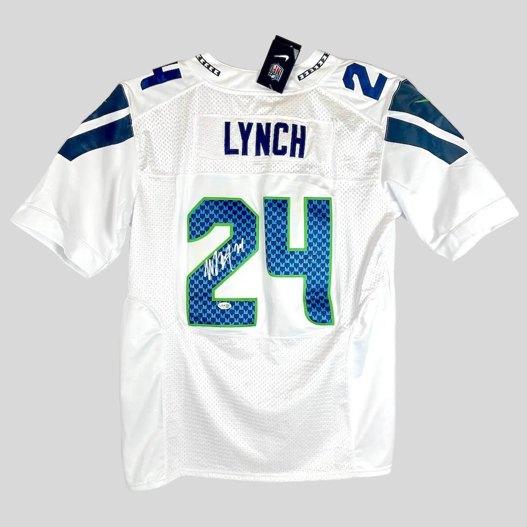 White Seahawks football jersey with 'LYNCH' and number '24' on the back, featuring a silver autograph over the '2'.