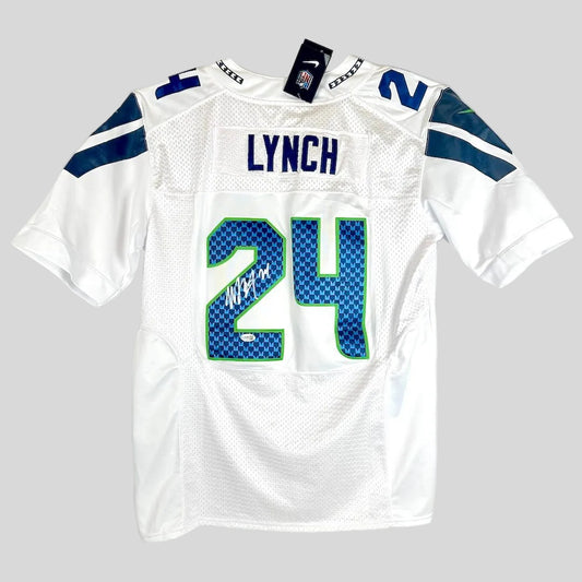 White Seahawks football jersey with 'LYNCH' and number '24' on the back, featuring a silver autograph over the '2'.