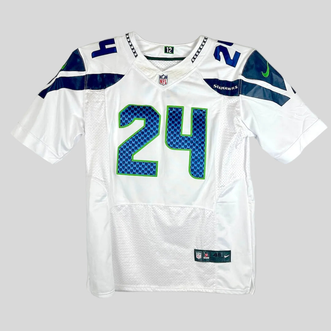 A white Seattle Seahawks football jersey with the number 24 on the front, featuring blue and green patterned numbers.