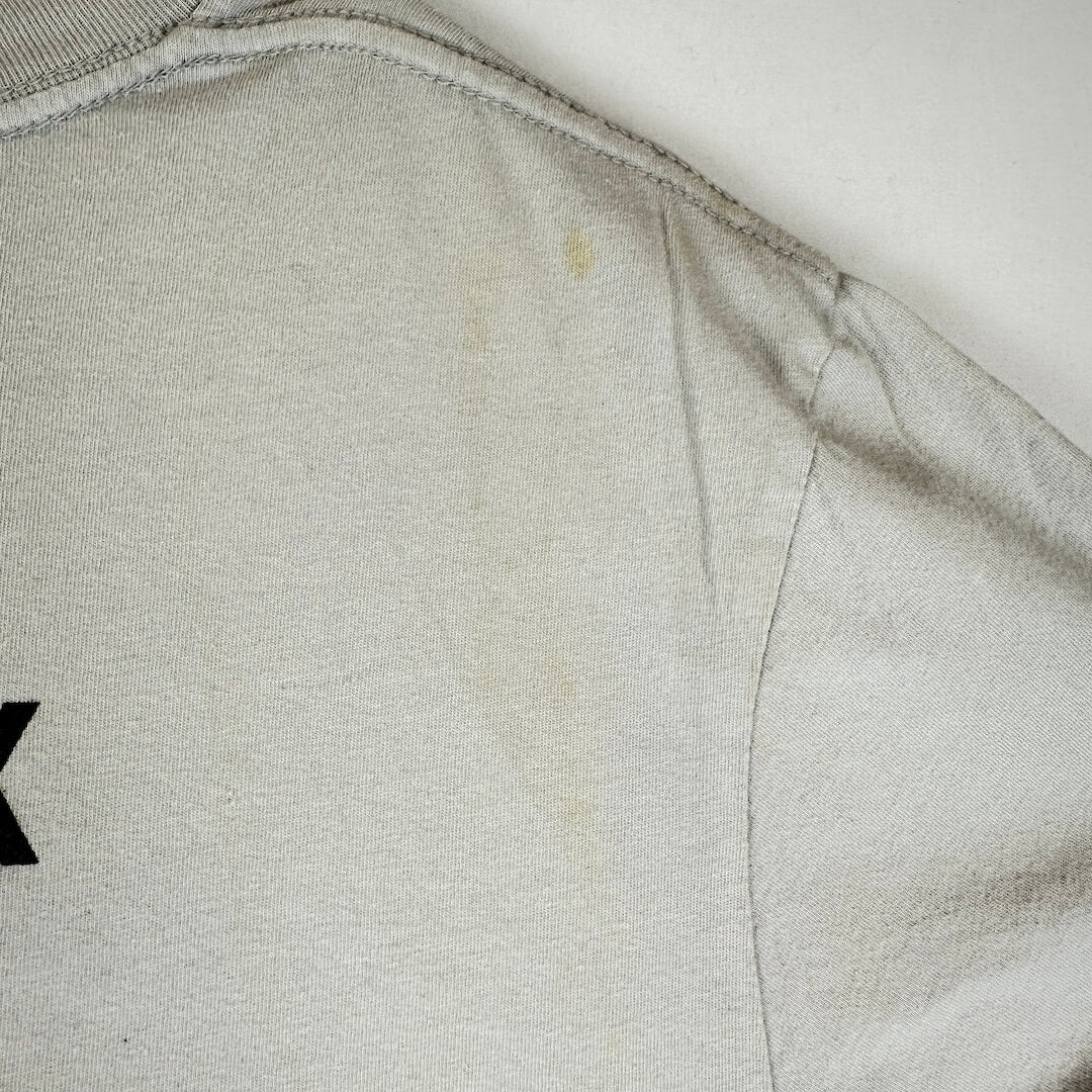 Close-up of a light gray or off-white fabric surface with visible staining or discoloration.