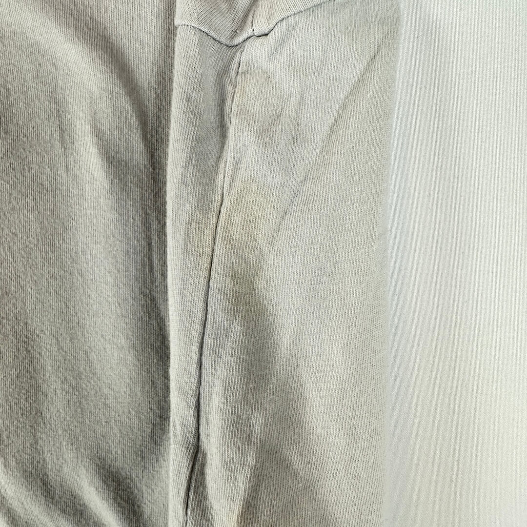 A close-up of a light gray ribbed fabric, showing the texture and a seam detail.