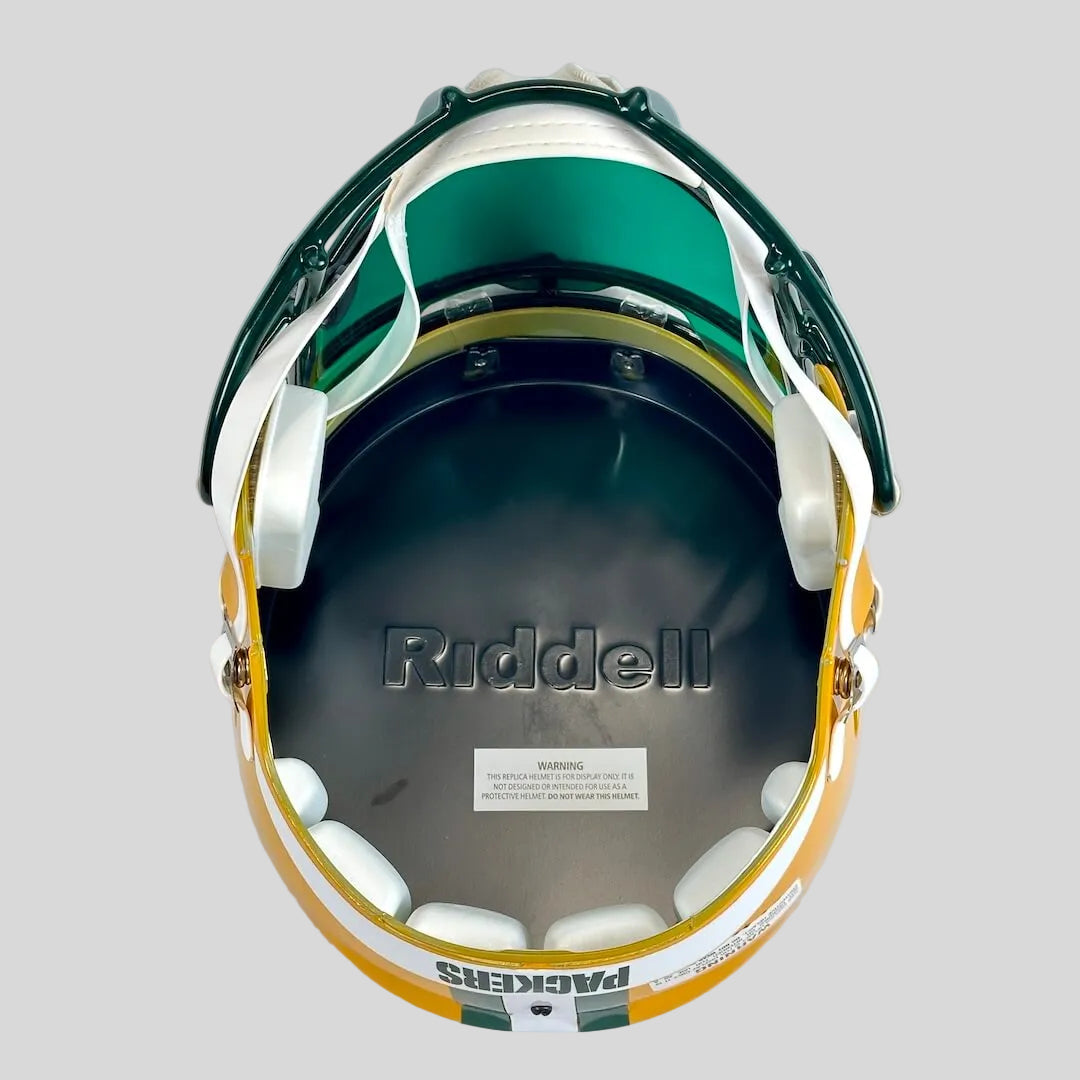 The inside of a Green Bay Packers Riddell football helmet, showing the black liner, white chin straps, and yellow and green outer shell.