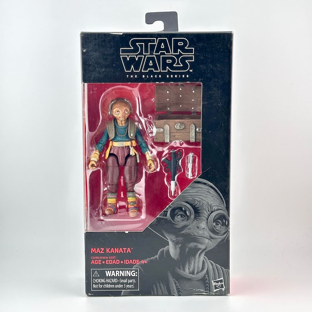 Star Wars Black Series action figure in its original window packaging; figure in brown with several accessories. 