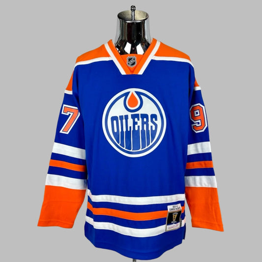 Jersey blue body & long sleeves, orange shoulders, white/orange stripes around waist & wrists. OILERS logo center chest.