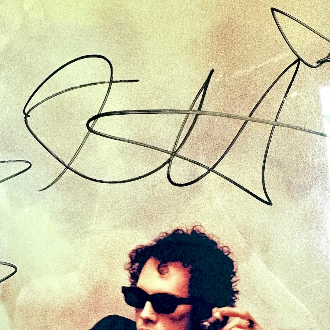 Person wearing sunglasses with a stylized signature above