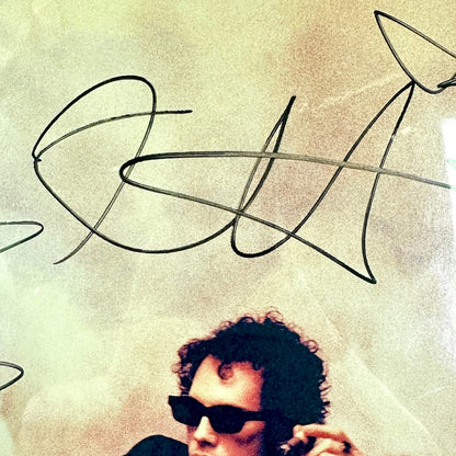 Person wearing sunglasses with a stylized signature above