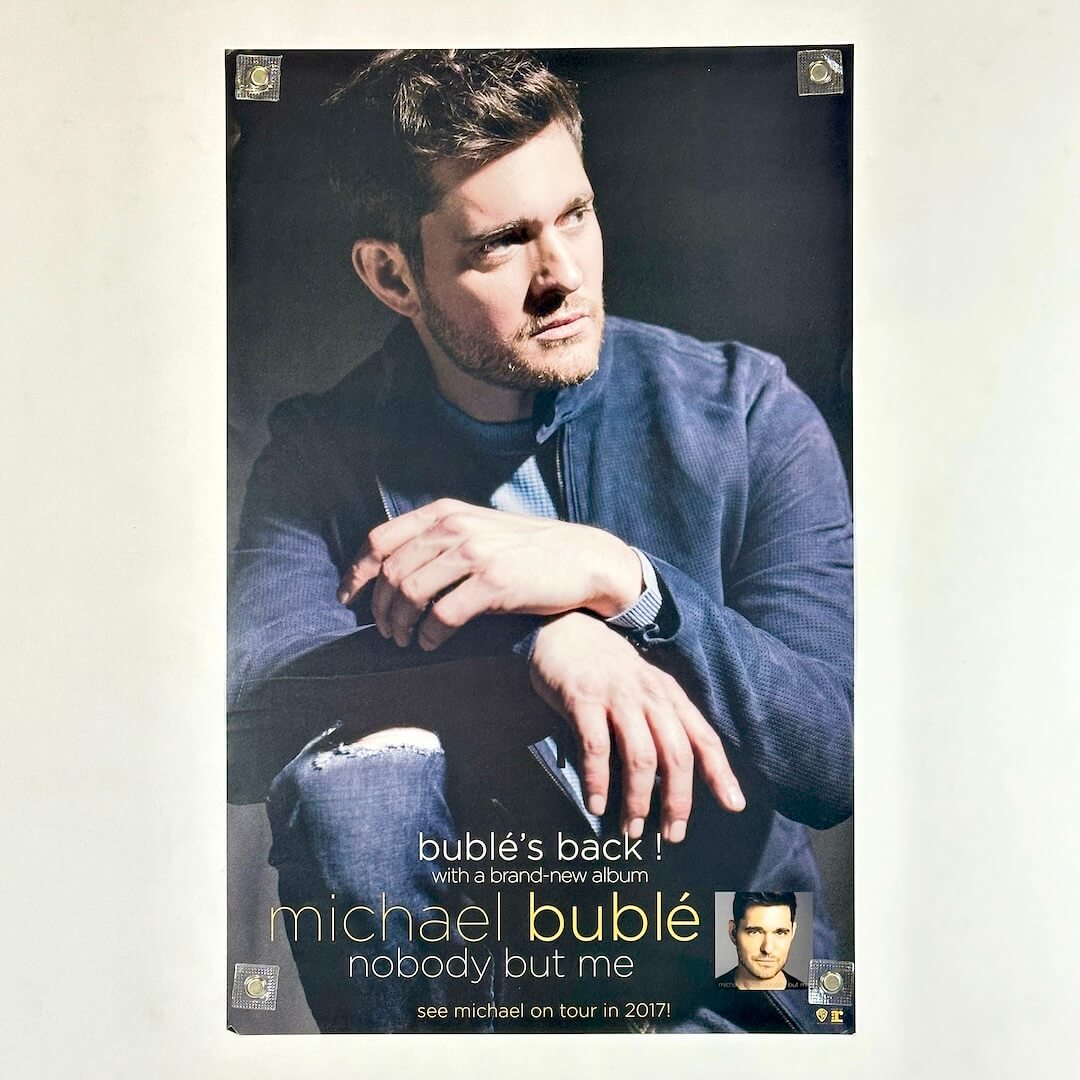 Poster of a man kneeling with his hands on his knee with artist and album name along bottom. 