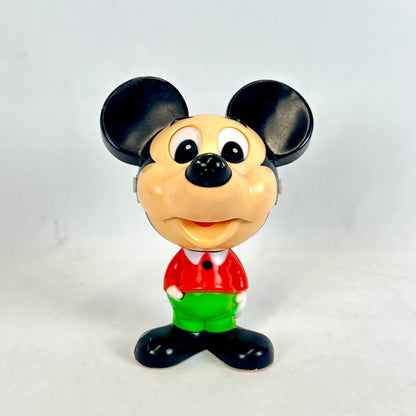 Toy figure of a character with a red shirt and green pants on a white background