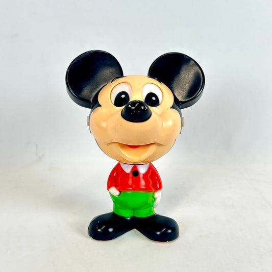 Toy figure of a character with a red shirt and green pants on a white background