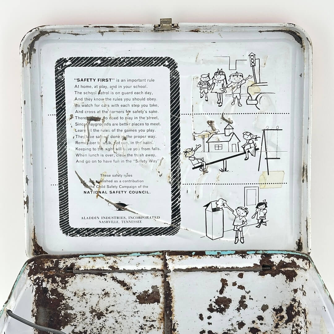 View of interior lid of lunchbox showing heavy wear but safety instructions and illustrations still clear. 