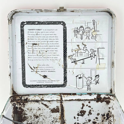 View of interior lid of lunchbox showing heavy wear but safety instructions and illustrations still clear. 