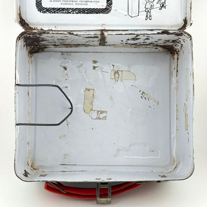 View of interior of metal lunchbox that is mostly white with some spots of rust and tape marks. 