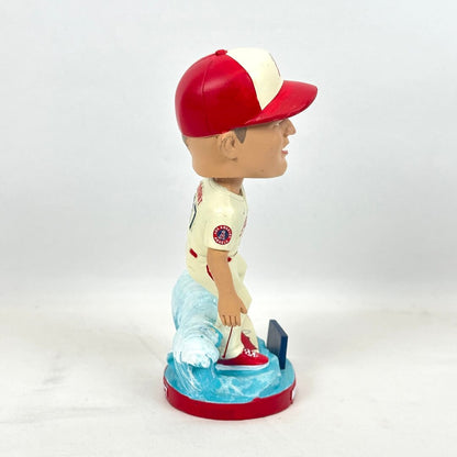 A baseball bobblehead figurine shown in side profile, wearing a red and white cap, a cream jersey.