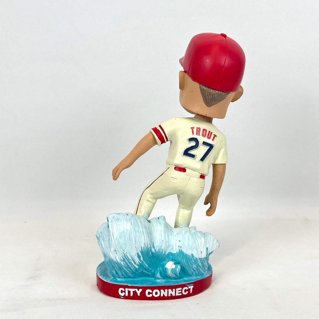 A bobblehead figurine of baseball player Trout wearing a red cap, cream jersey with red and navy lettering.
