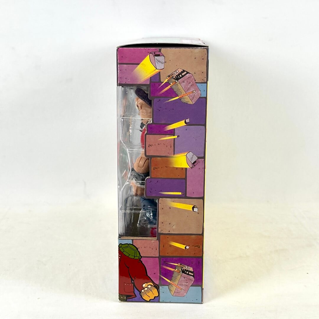Side view of packaging with animated bricks flying from window, photographed on a light background.