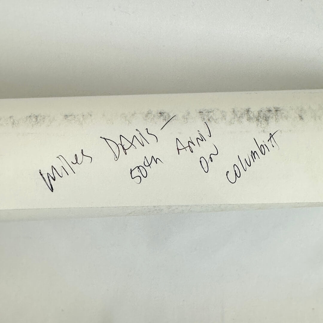 Rolled poster with artist name in pen against white background. 