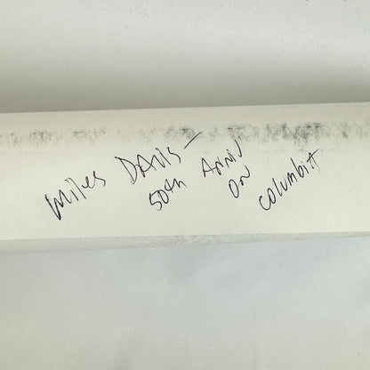 Rolled poster with artist name in pen against white background. 