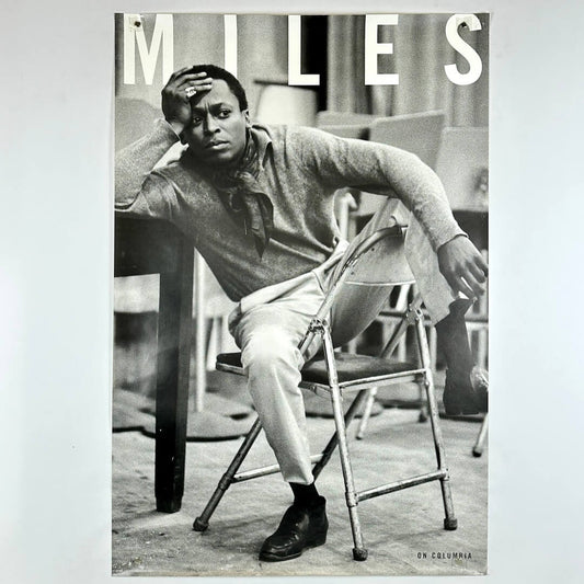Poster of  Miles Davis sitting on a chair, featuring the name 'Miles' at the top.