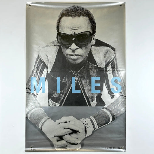Poster of a person wearing sunglasses with 'MILES' text on a gray background