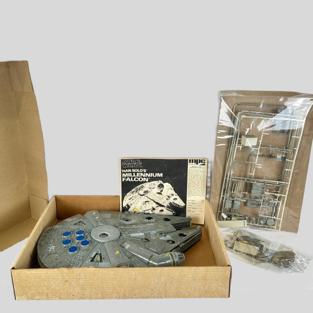 Model of a spaceship in an open cardboard box with packaging materials on a white surface.