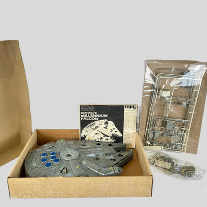Model of a spaceship in an open cardboard box with packaging materials on a white surface.