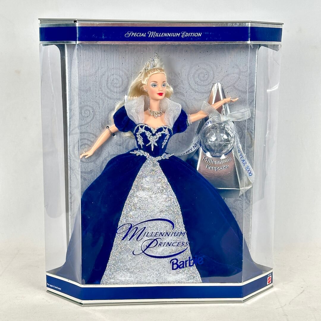 Barbie doll in a blue and silver dress with a clear packaging box on a white background