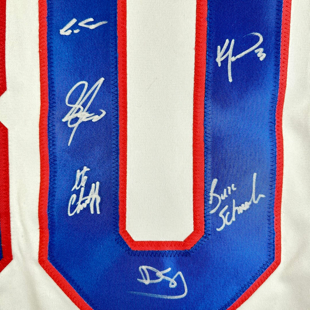 Close-up of a sports jersey with autographs on a blue and red border