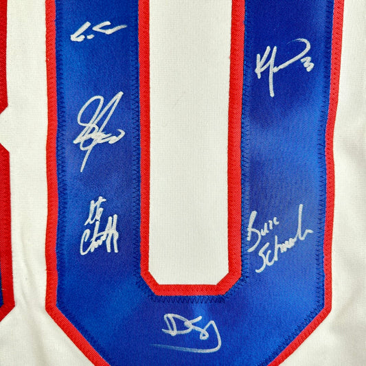 Close-up of a sports jersey with autographs on a blue and red border