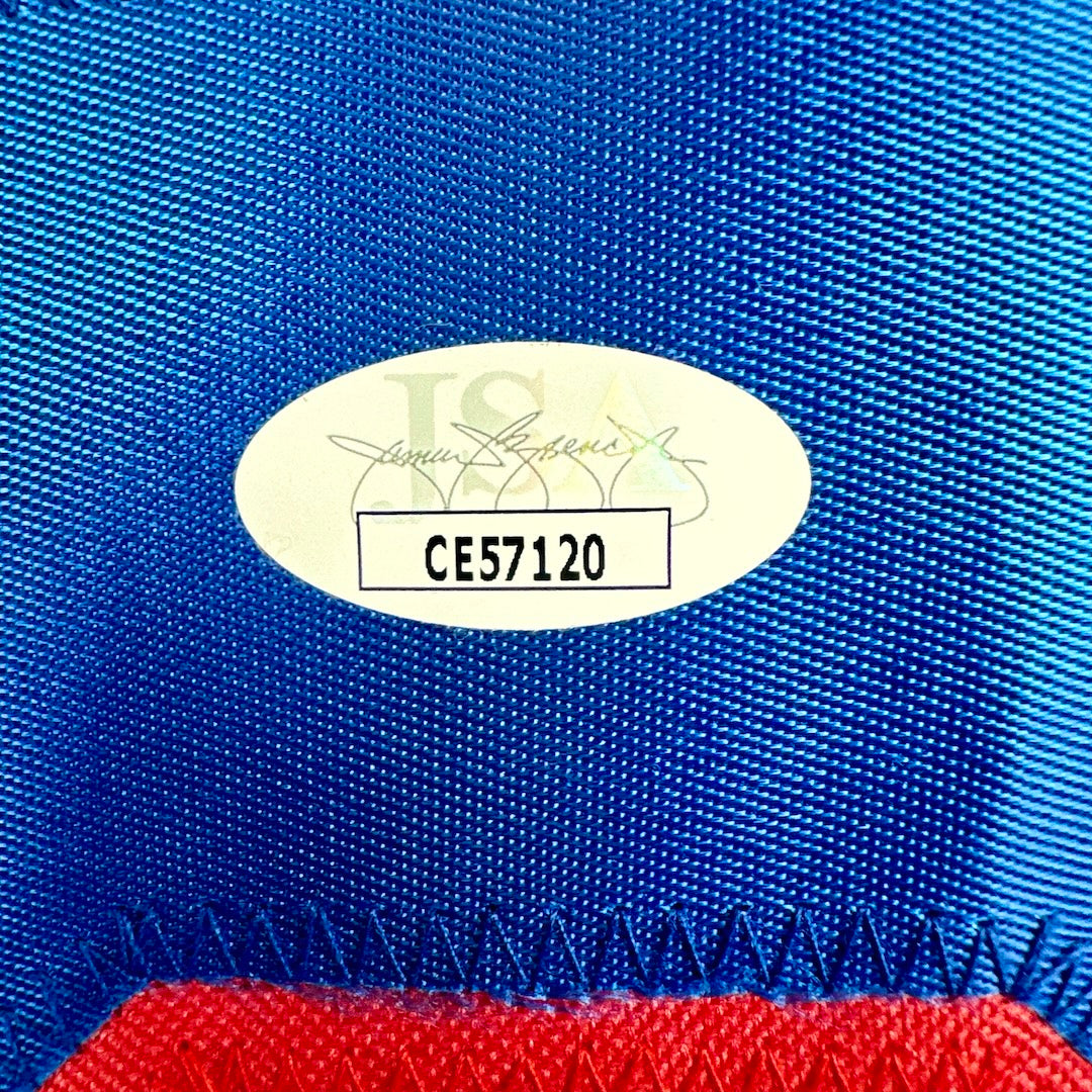 Close-up of a blue fabric with a gold label and red material at the bottom.