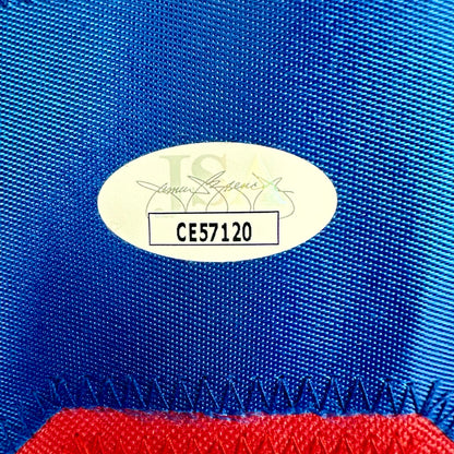 Close-up of a blue fabric with a gold label and red material at the bottom.