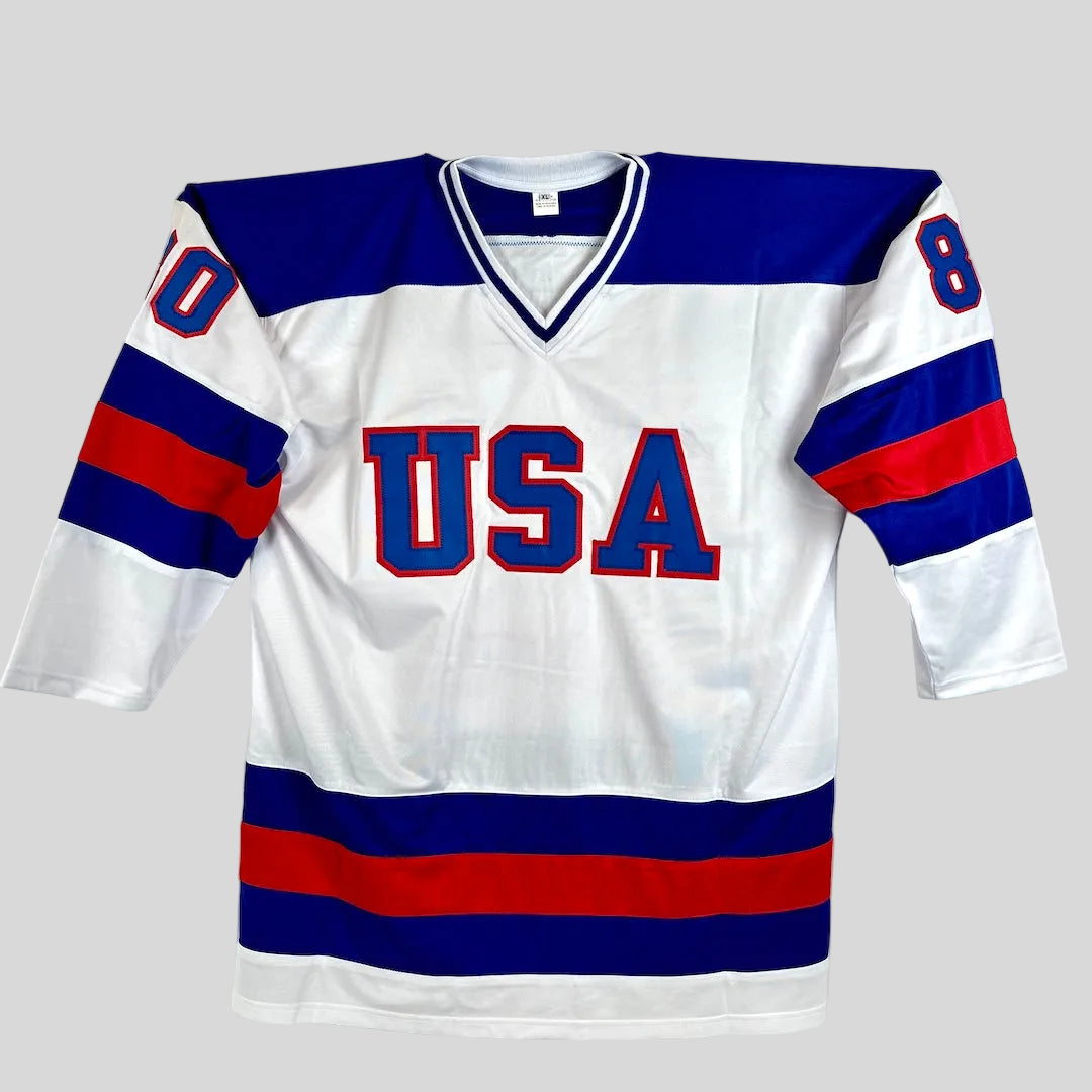 White hockey jersey with blue and red accents featuring 'USA' on a white background