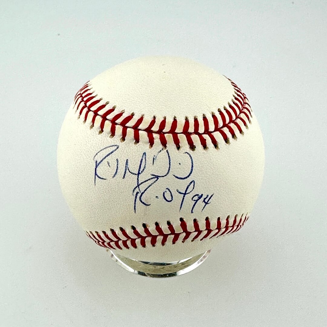 An autographed baseball with blue ink signatures dated displayed on a clear acrylic stand.