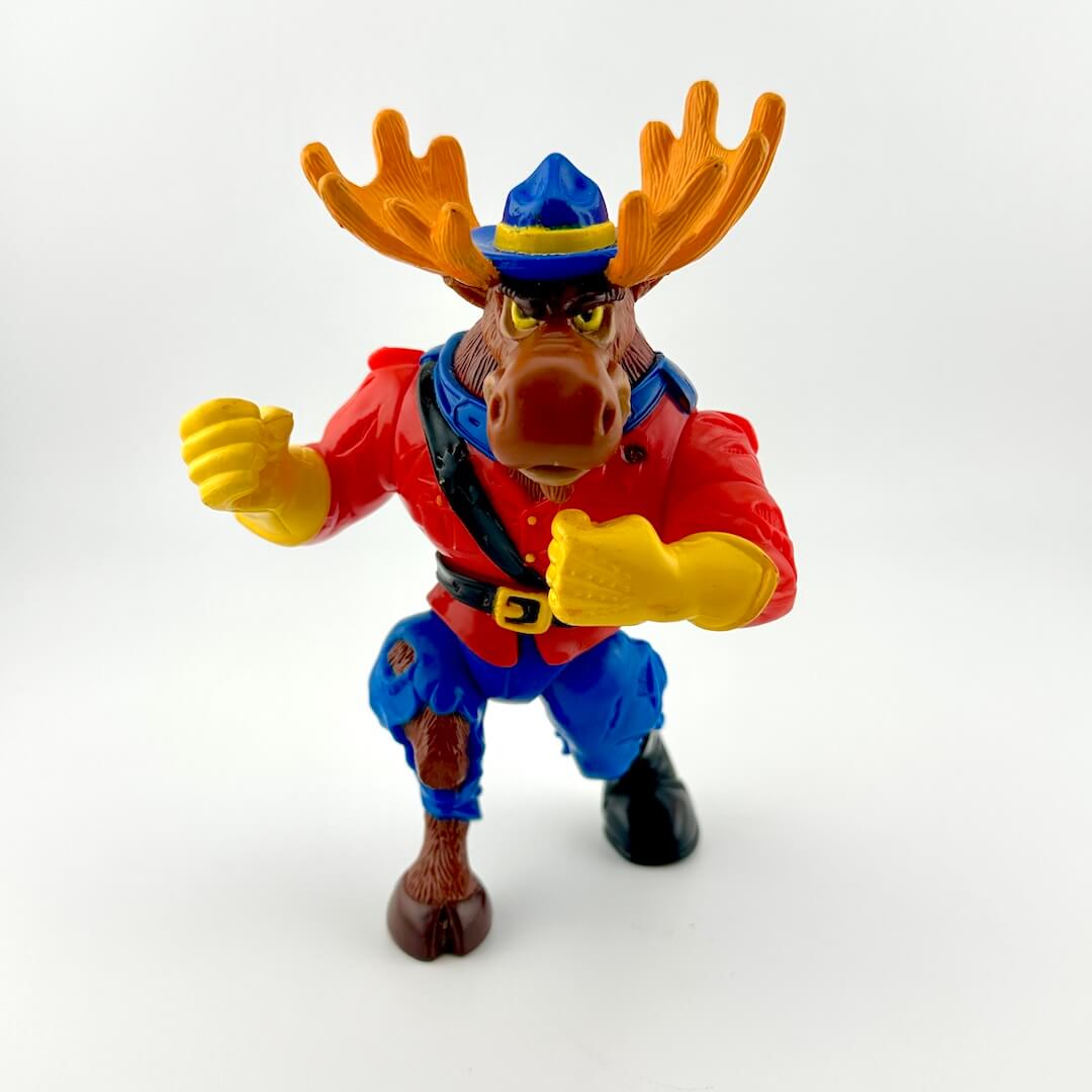 Toy figure of a moose in a red jacket and blue pants on a white background