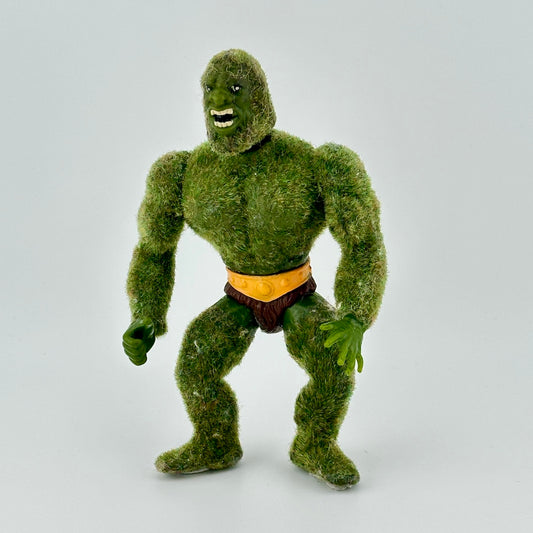 Forest green flocked male action figure with brown loincloth with yellow belt. Figure is bearing teeth.