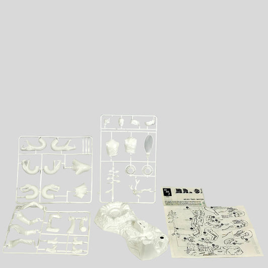 Set of white plastic mold components and instructions on a light gray background