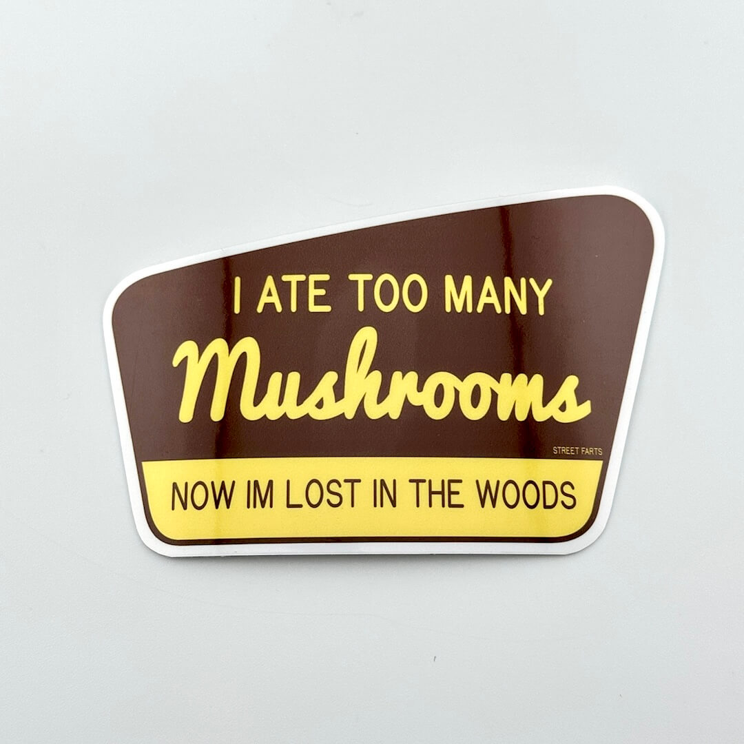 Sticker with text 'I ATE TOO MANY Mushrooms NOW IM LOST IN THE WOODS' on a brown and yellow background