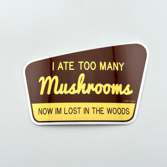 Sticker with text 'I ATE TOO MANY Mushrooms NOW IM LOST IN THE WOODS' on a brown and yellow background