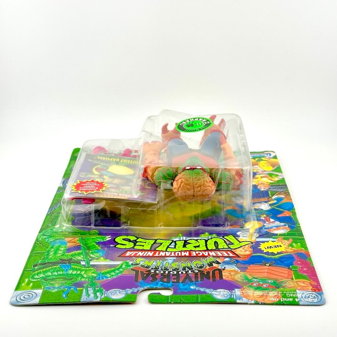 Toy figure in packaging on a colorful mat with 'Teenage Mutant Ninja Turtles' branding.