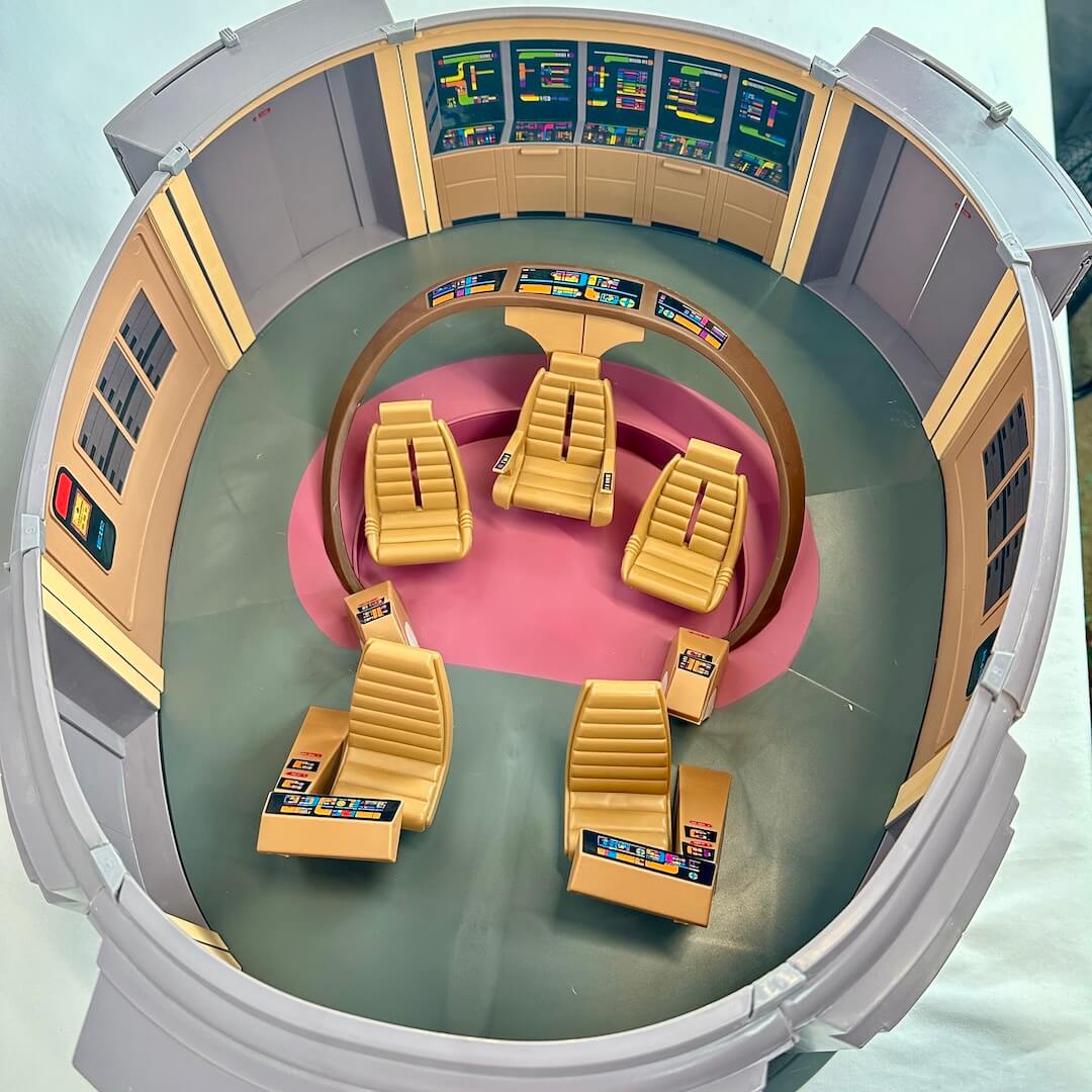 Control room with yellow chairs and multiple screens on a light blue background
