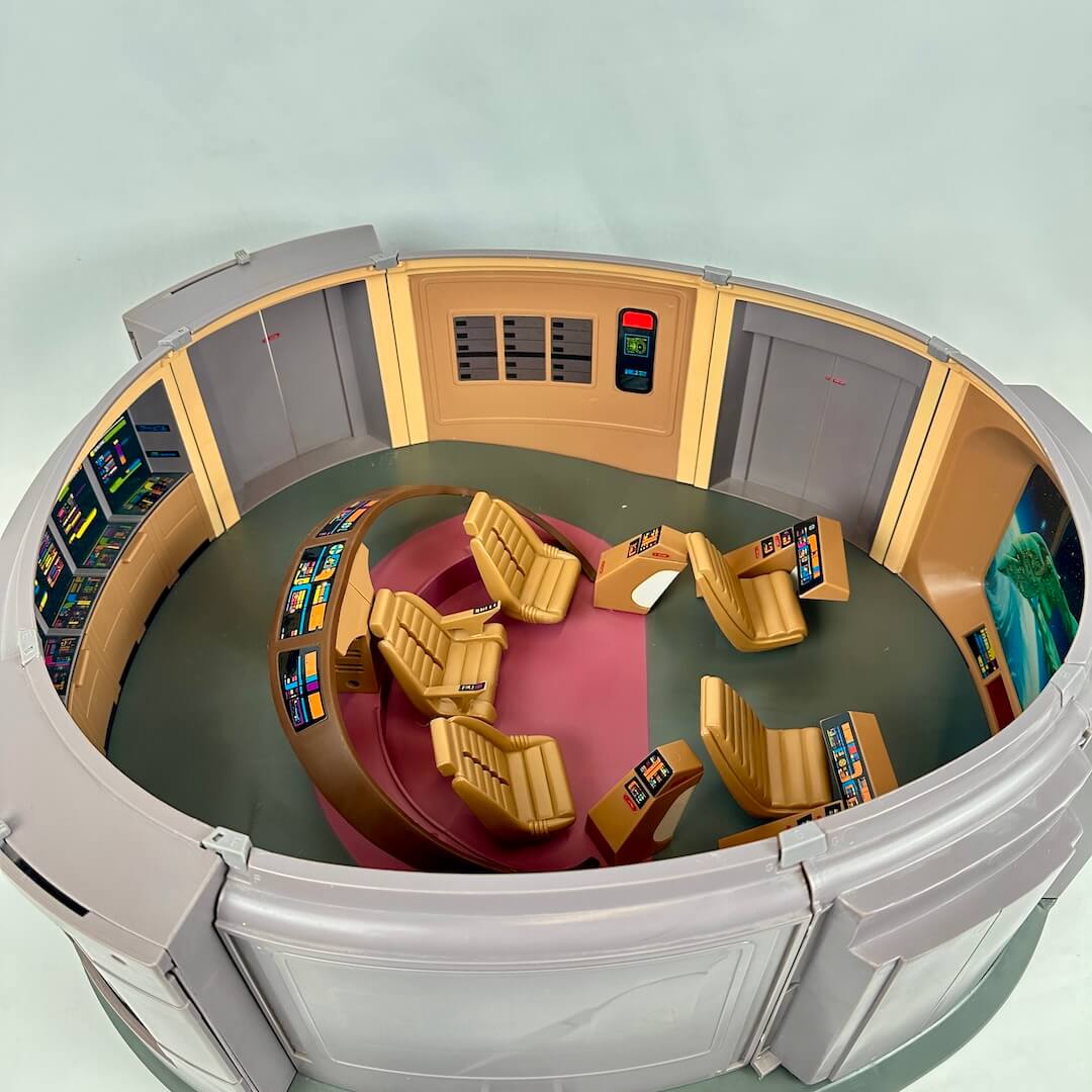 Control room interior with round table and chairs, likely from a science fiction setting.