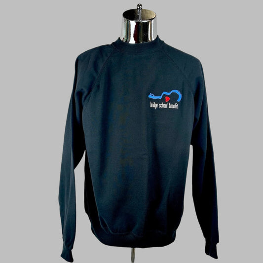Black crew neck sweatshirt with embroidered logo on breast of half guitar laying down with event title below. 