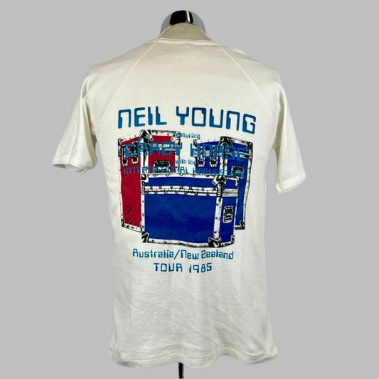 Back of white short sleeve shirt with three equipment cases behind tour info in blue text. 