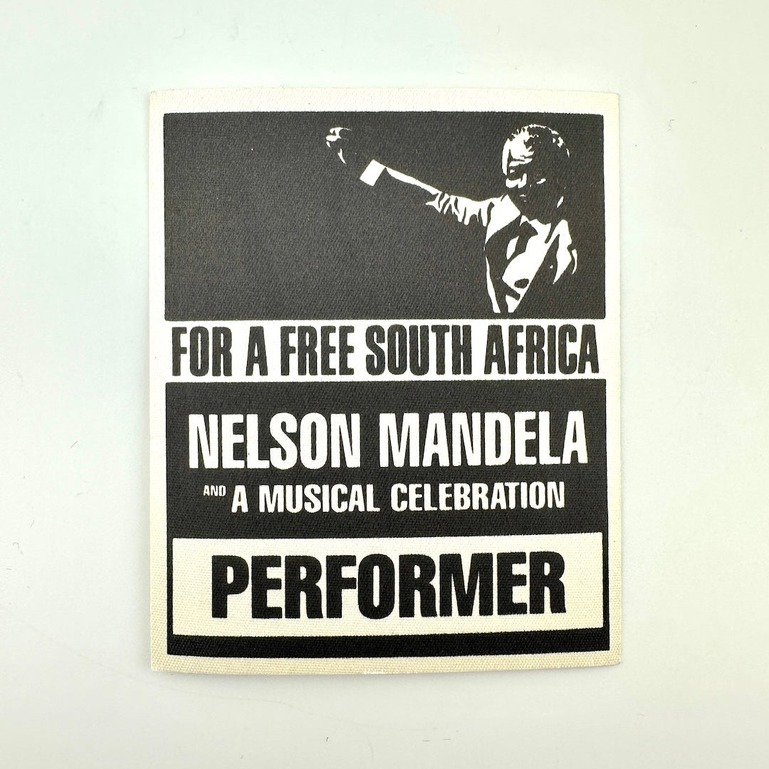 A square black and white printed pass featuring a portrait of Nelson Mandela raising his hand, with the text 'FOR A FREE SOUTH AFRICA'